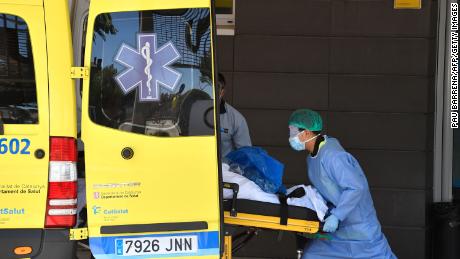 A healthcare worker carries a patient out of an ambulance outside the Arnau de Vilanova University Hospital in Lleida on July 4, 2020. - Spain&#39;s northeastern Catalonia region locked down an area with around 200,000 residents around the town of Lerida following a surge in cases of the new coronavirus.